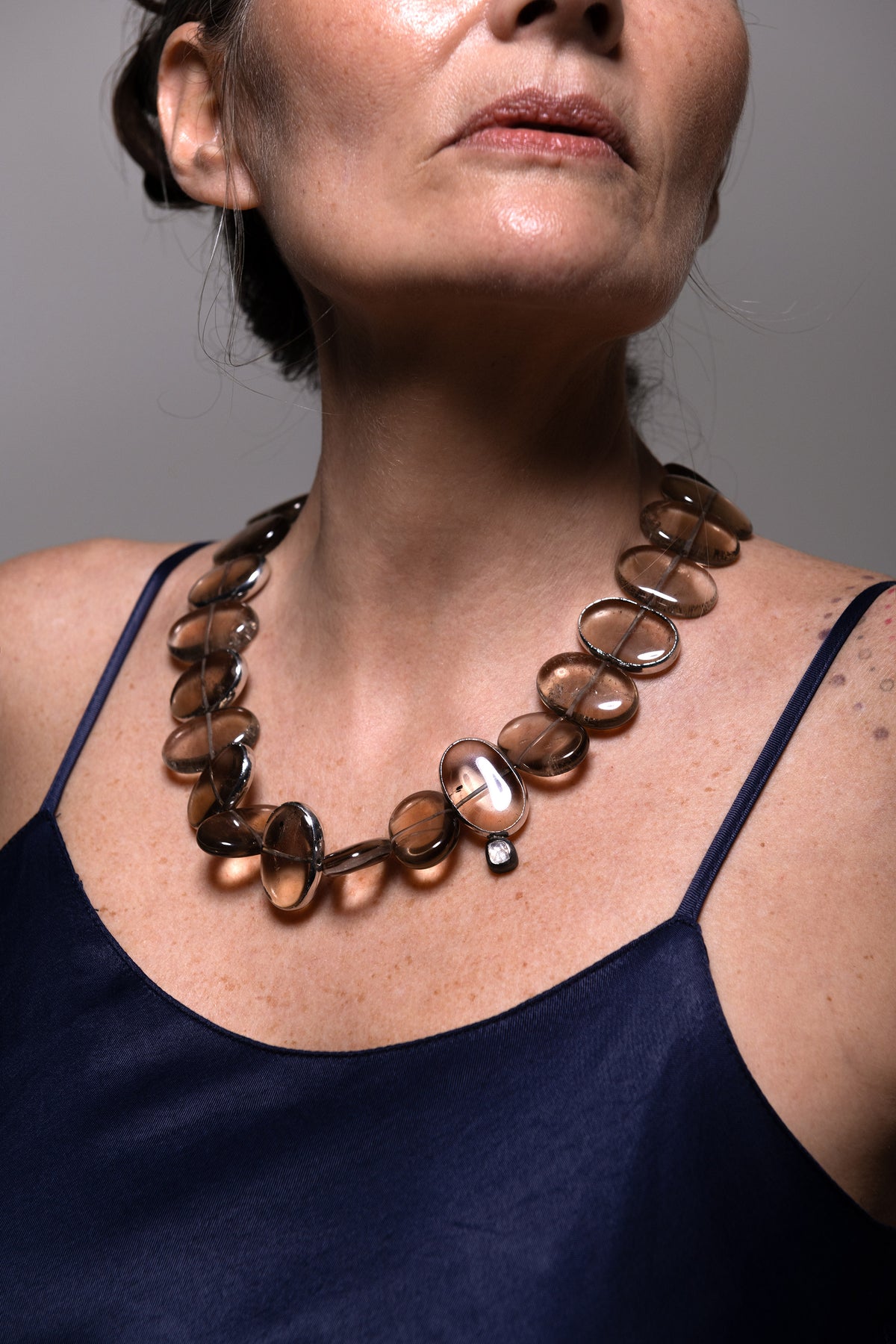 Model in a navy camisole wearing Flux smoky quartz necklace, diamond accent at the front