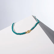 Bébé Duo turquoise necklace with signature 24k gold-plated Bébé Lock on white surface — House of Sól modular fine jewelry