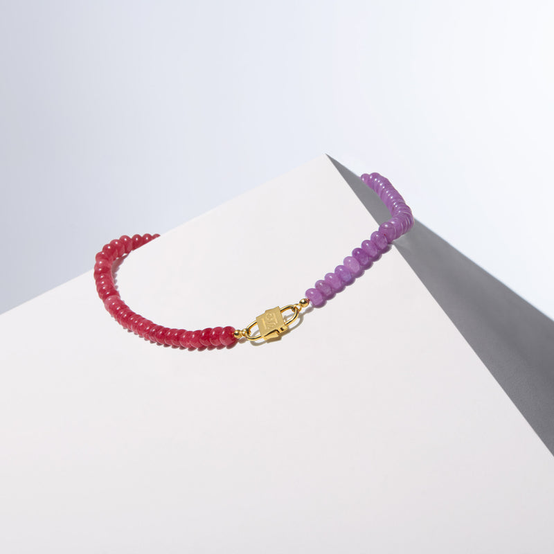 A two-tone gemstone beaded necklace with pink and purple jade beads, featuring a gold-filled silver bead with a sandblasted finish as a centerpiece, displayed against a simple background.