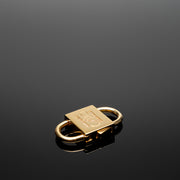 HoS Lock Diamond Edition with its monogram set in brown diamonds, lying on a reflective dark surface