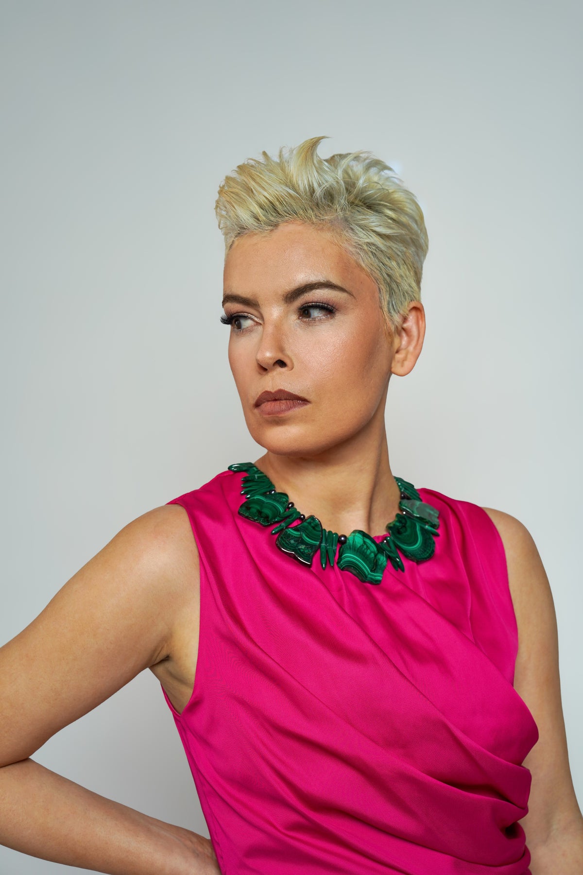 Anohni malachite necklace on model glancing sideways with hand on hip, pink sleeveless dress