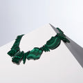 Anohni malachite necklace with large cut stones, spike beads and small black pearls on a white block