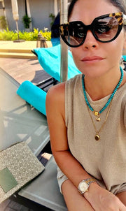 Bebe Turquoise necklace with HoS Lock worn poolside, plus a small charm and a gold-tone pendant necklace
