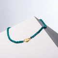 Bebe Turquoise necklace of rondelle turquoise beads closed with gold-tone HoS Lock on a white block