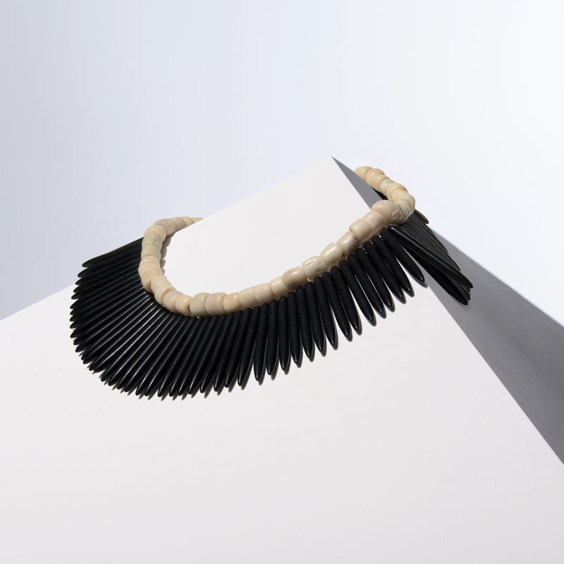 Black Nefertiti white coral and black howlite spike necklaces draped together over a white block