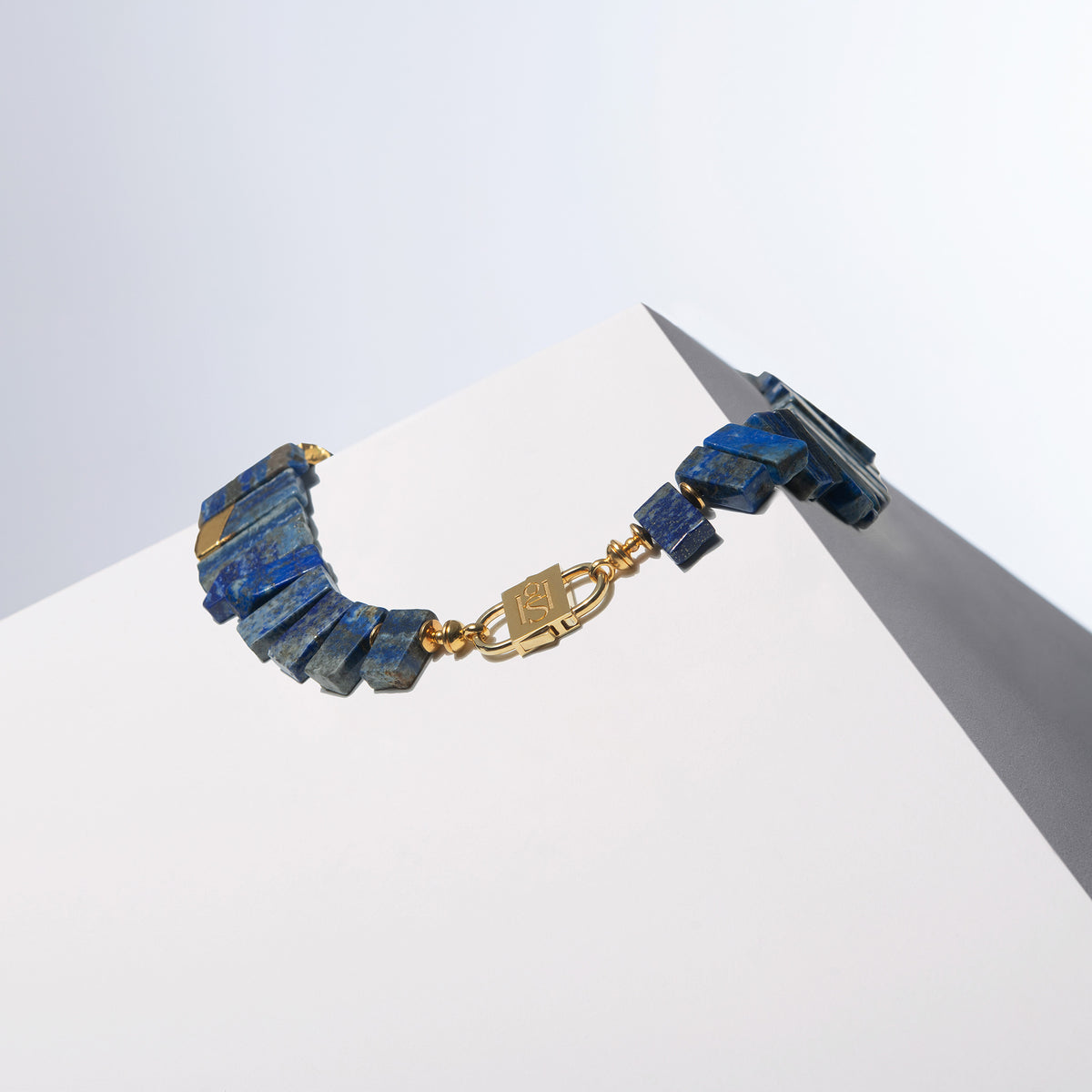 Back view of the Doris lapis lazuli necklace with gold-tone HoS Lock on a white block