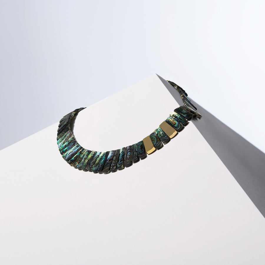 Golden Paua iridescent sea shell necklace with two gold-tone accents on a white block