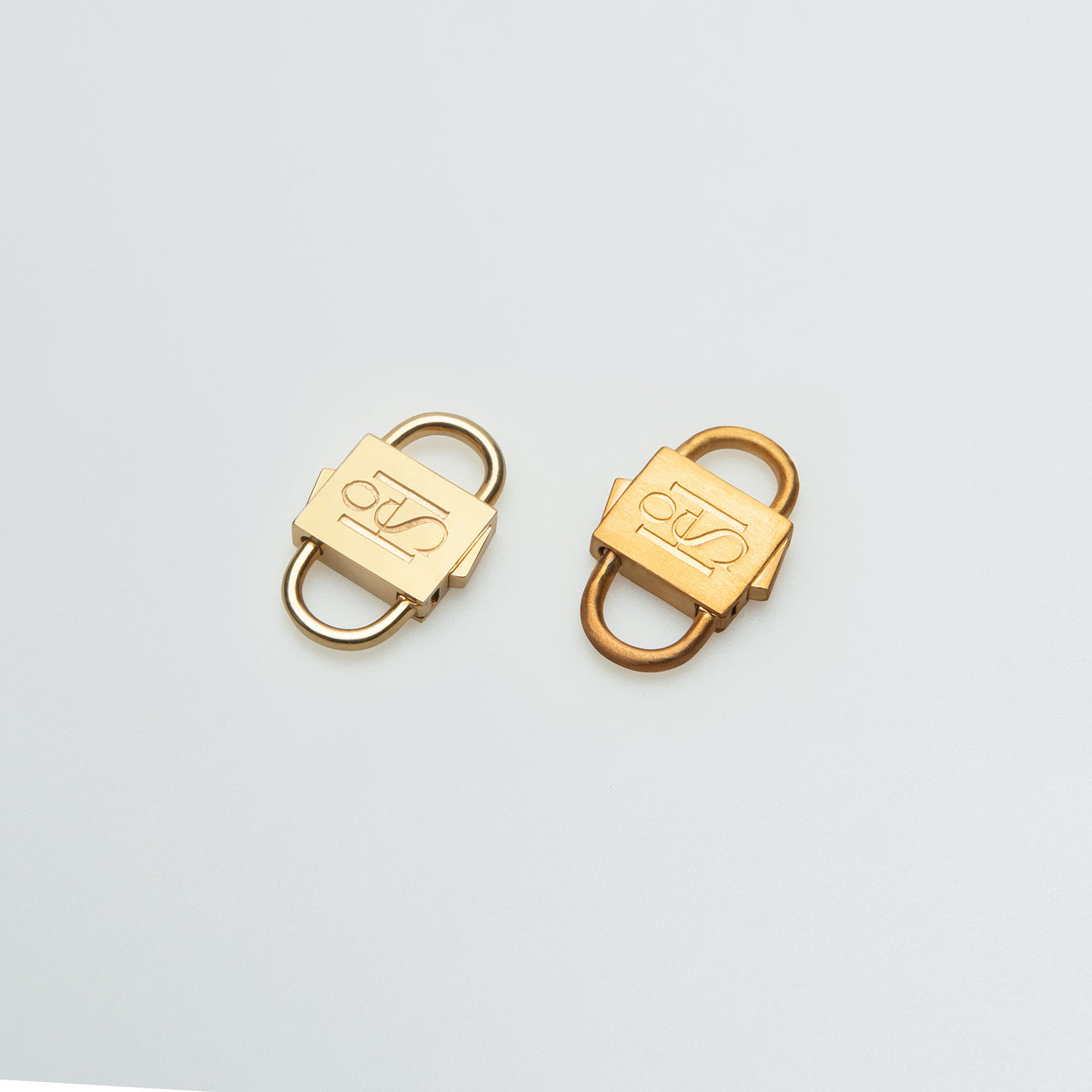Two gold-tone HoS Locks with different finishes side by side on a white surface
