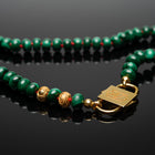 Iris malachite necklace detail with gold-tone HoS Lock and gold-filled ornaments on a black surface