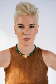 Model in a brown suede top wearing the Iris malachite necklace with gold-tone HoS Lock