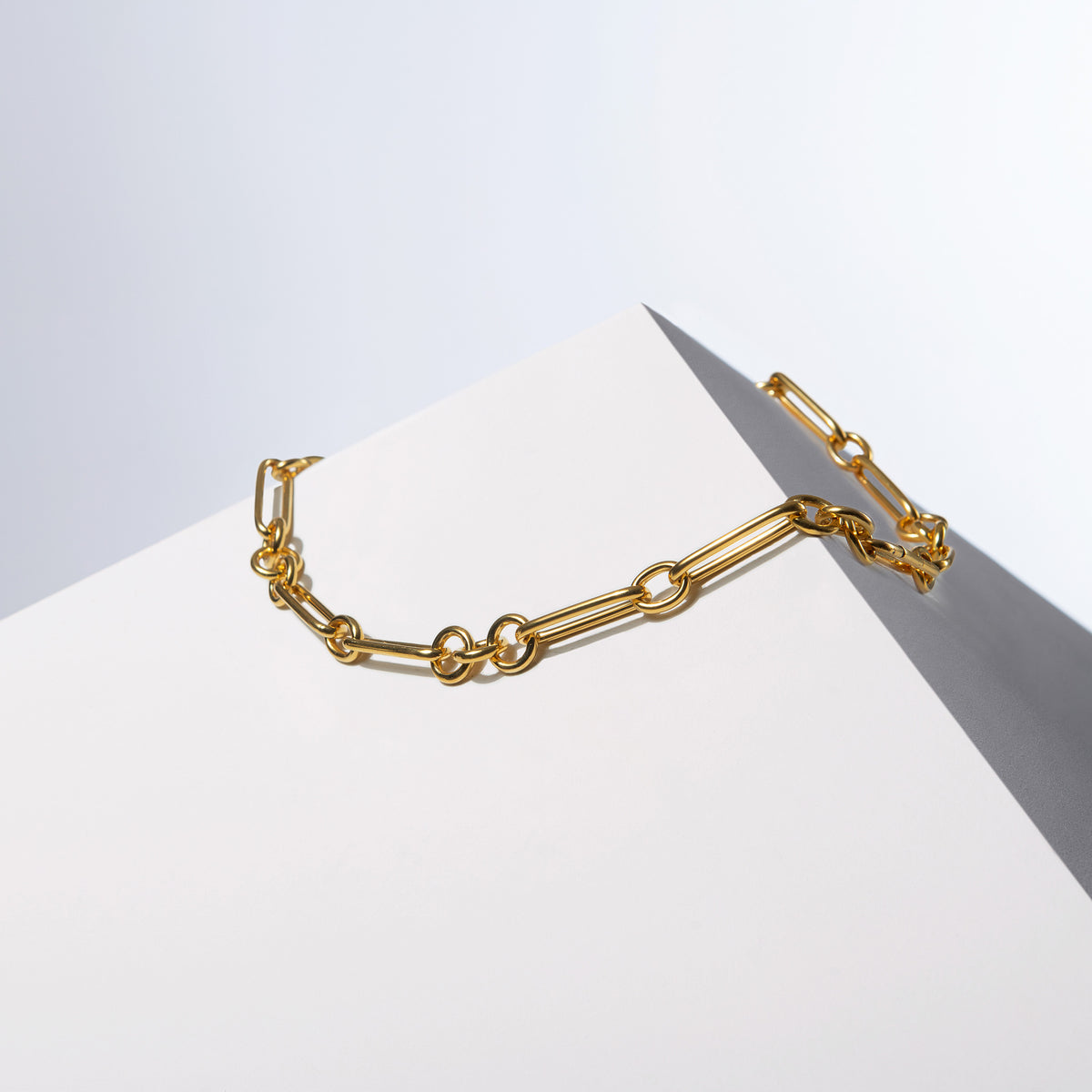 Medium Trombone Chain Necklace shown without HoS Lock, gold-tone links on a white block