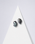 Perle Noire peacock baroque pearl earrings, a pair on a white pyramid against a pale backdrop