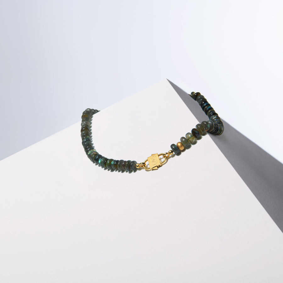 Po labradorite bead necklace with gold-tone HoS Lock draped over a white block