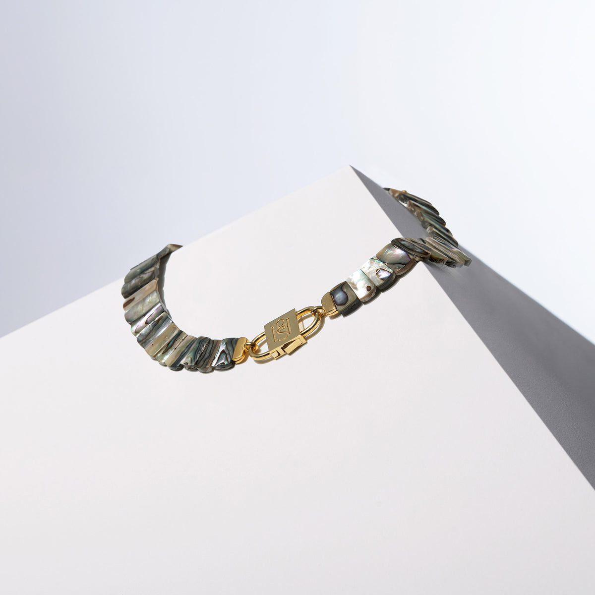 Queen Paua sea shell necklace with a gold-tone HoS Lock facing forward on a white block