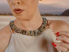 Close-up of the Queen Paua sea shell necklace with white sapphires on the neck, beige satin top