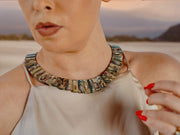 Close-up of the Queen Paua sea shell necklace with white sapphires on the neck, beige satin top