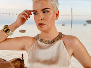 Queen Paua sea shell necklace on a model in a beige satin halter top, beach backdrop