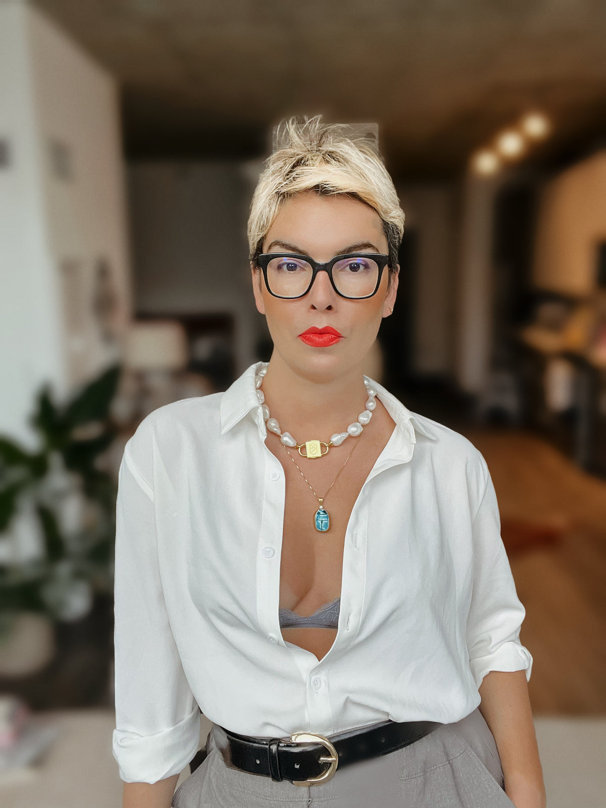 Woman in a white shirt wearing the Scarab charm on a chain and a baroque pearl necklace