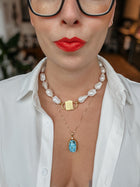 Scarab charm on a fine chain worn below a baroque pearl necklace with HoS Lock