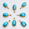 Eight Scarab charms of blue Egyptian faience with white sapphires arranged in a ring