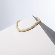 White Coral necklace, a single row of small coral beads draped over a white block