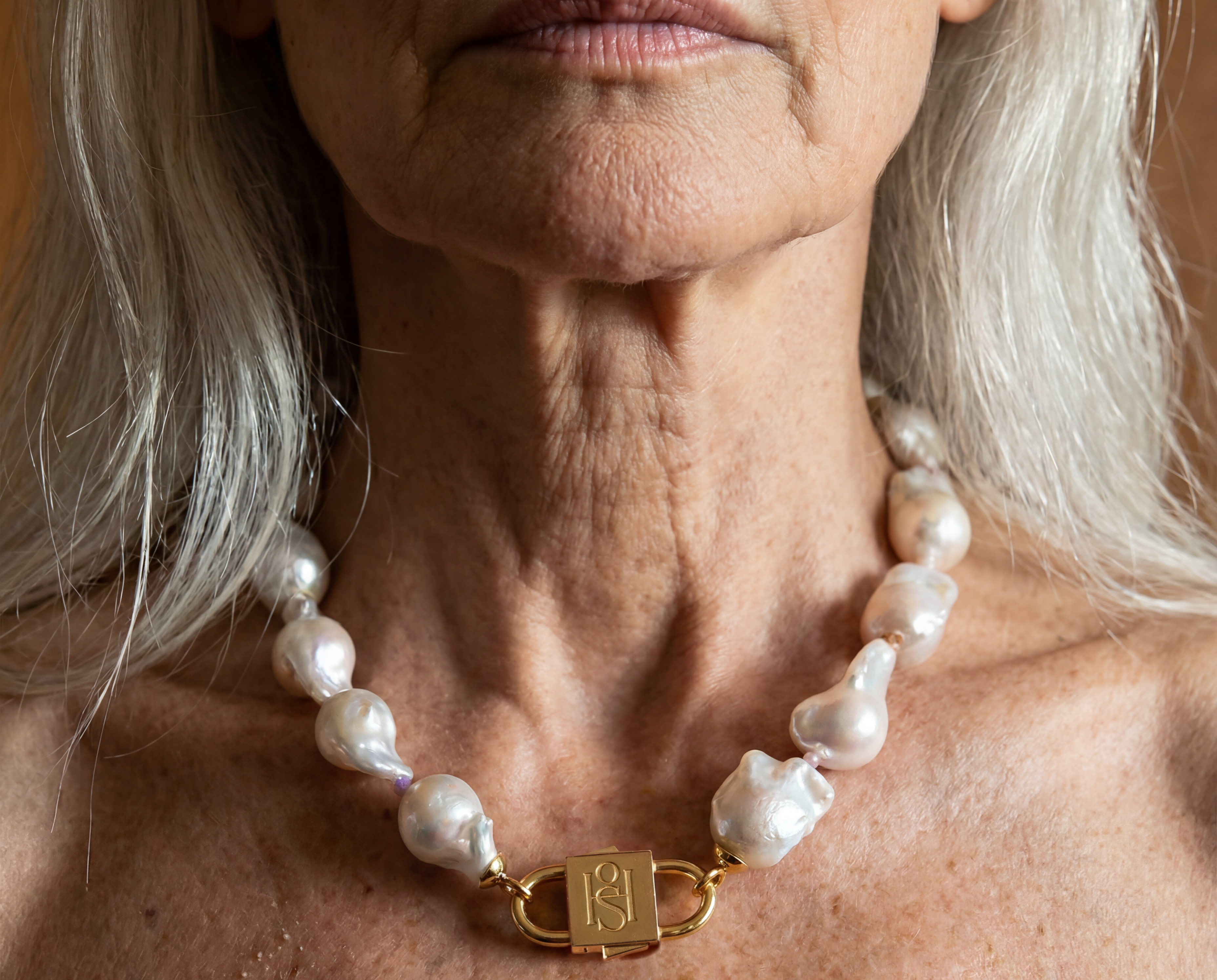 Ostrea baroque pearl necklace with engraved gold lock clasp by House of Sól, worn by silver-haired model.