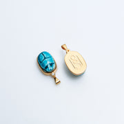 Two Scarab charms side by side, one showing the faience front and one the HoS monogram back