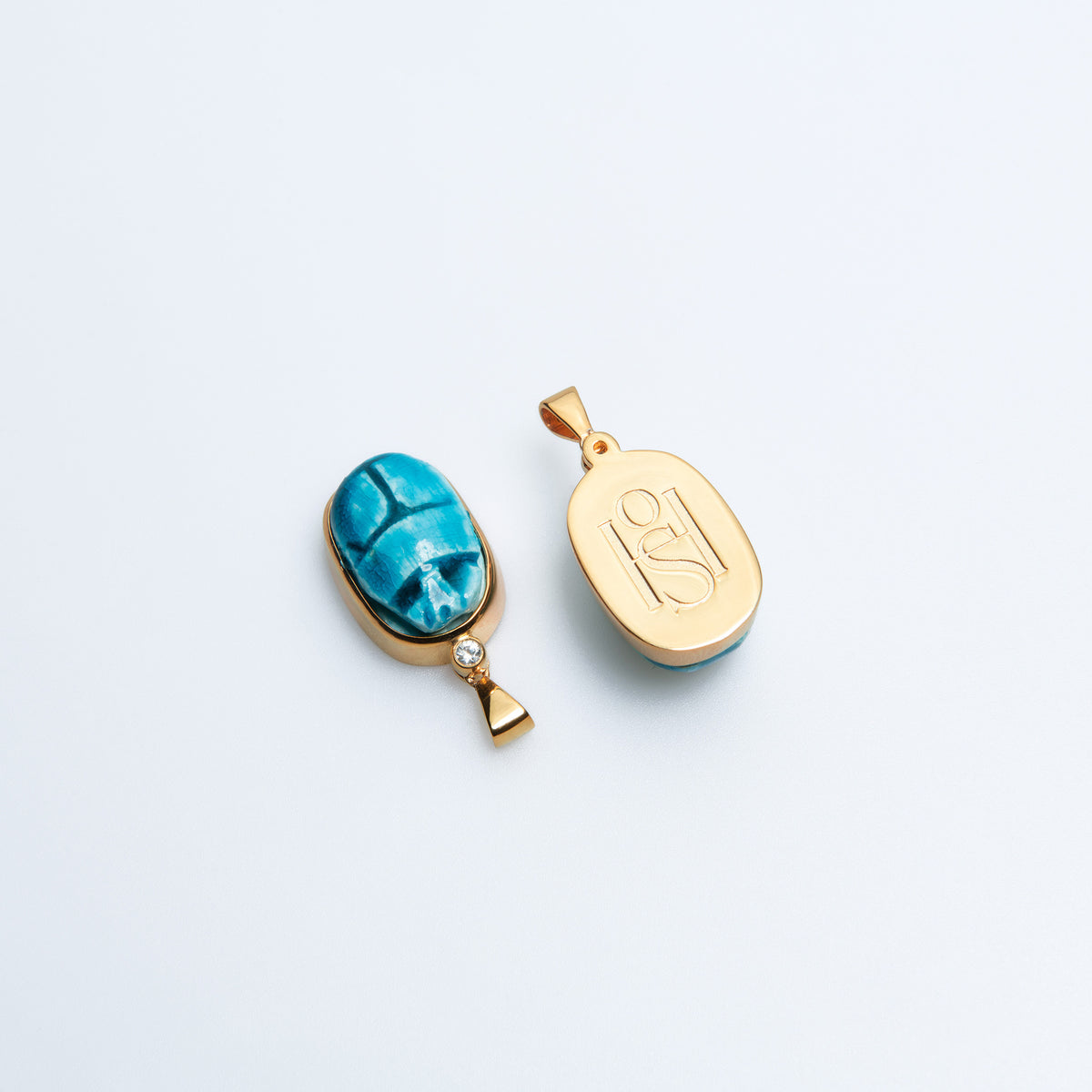 Two Scarab charms side by side, one showing the faience front and one the HoS monogram back