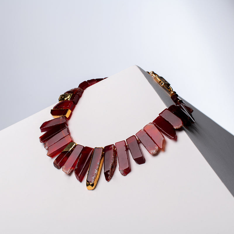 Aliye red agate necklace with gold-tone accents and HoS Lock on a white block