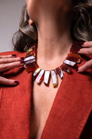 Close-up of the Aliye red agate necklace at the neck, framed by rust-colored jacket lapels