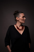 Model in a black V-neck top wearing the Aliye red agate necklace, shown in profile