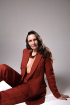 Model in a rust-colored suit seated on the floor wearing the Aliye red agate necklace