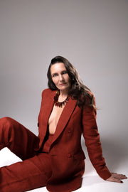 Model in a rust-colored suit seated on the floor wearing the Aliye red agate necklace