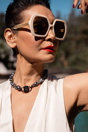 Cosmos black baroque pearl necklace with black HoS Lock, model in white sunglasses and cream top outdoors