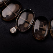 Close-up of Flux smoky quartz ovals, one silver-tone rimmed, with a diamond accent on black