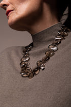 Flux smoky quartz necklace over a taupe turtleneck, close crop of the model's neck in profile