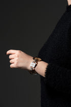 Fluxes smoky quartz bracelet on the wrist with the HoS Lock facing the camera, black knit sleeve