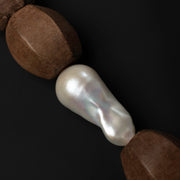 Close-up of the Light Walden fireball baroque pearl between faceted light brown wood beads on black