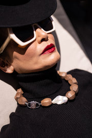 Reclining model in a black turtleneck wearing Light Walden wood and baroque pearl necklace with HoS Lock