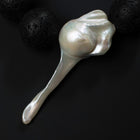 Close-up of the large fireball baroque pearl on the Luna necklace beside black lava stones