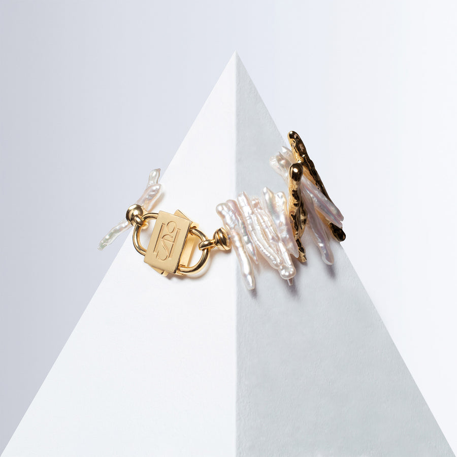 Medusa bracelet of elongated pearls and textured gold-tone pieces with HoS Lock on a white pyramid