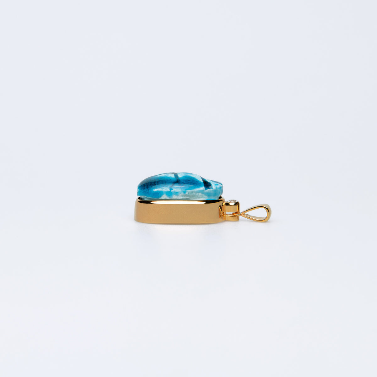 Side view of the Scarab charm showing its faience top, white sapphire and bail