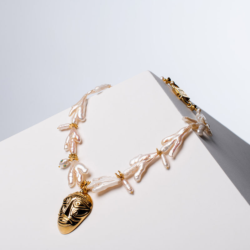 Sui Generis freshwater pearl necklace with gold-tone HoS Mask pendant and HoS Lock on a white block