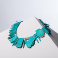 Tribe necklace of slab-cut and spike-cut turquoise howlite with pearls on a white block
