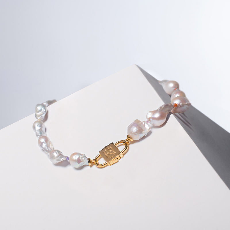 Ostrea necklace with baroque pearls and gold-clasp, displayed on a white surface.